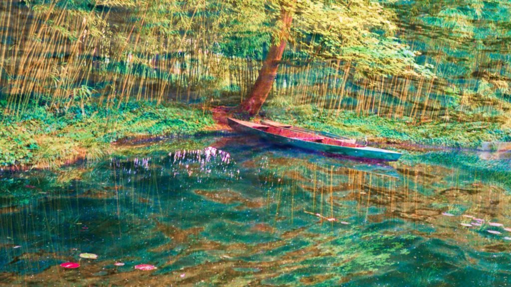 Photographie artistique d'une jolie barque qui flotte sur l'eau, entourée d'arbres, de branches et de feuilles. Image paisible de Giverny